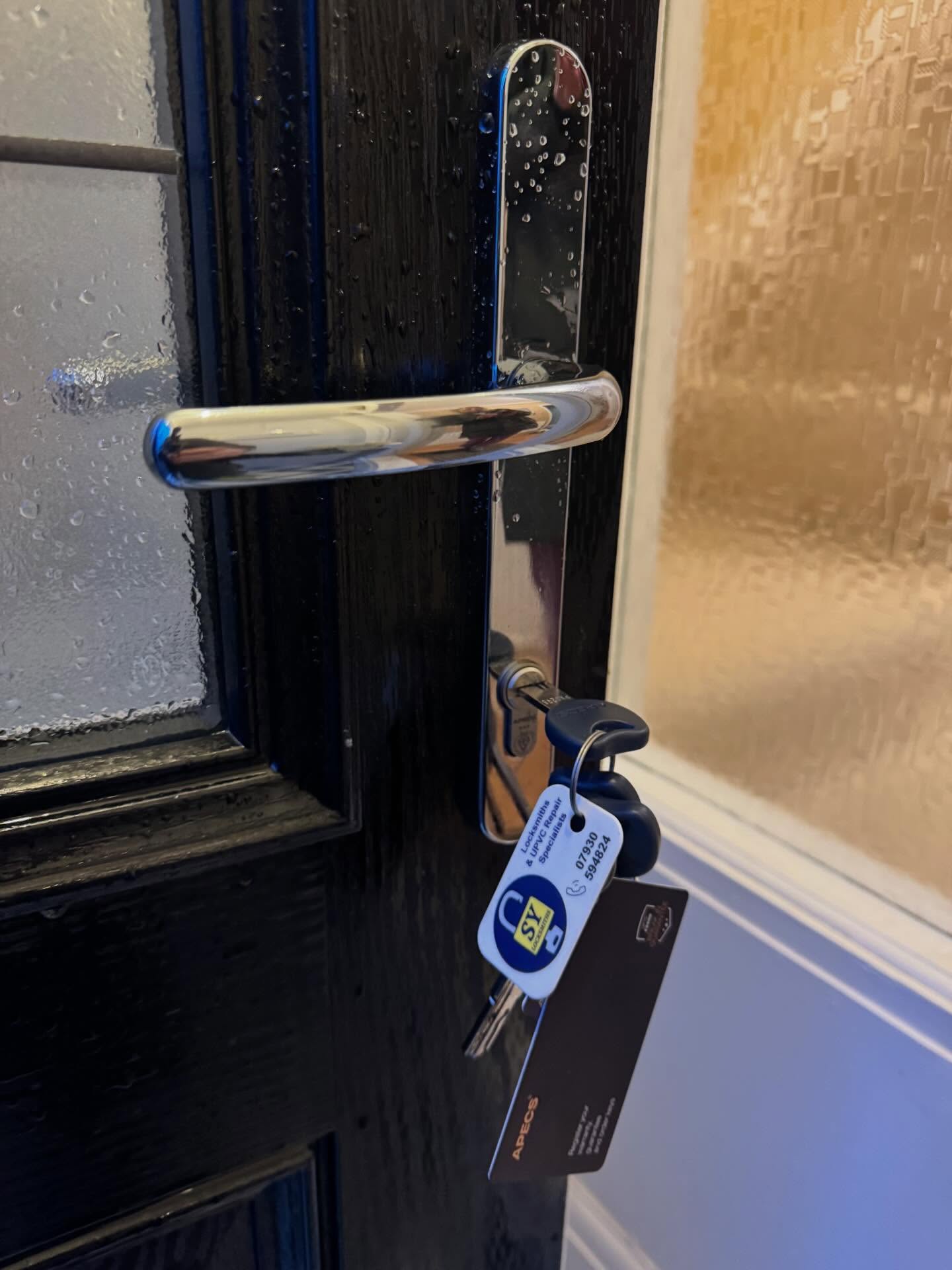 Close-up of a black door with a silver handle, anti snap lock and key on a white background