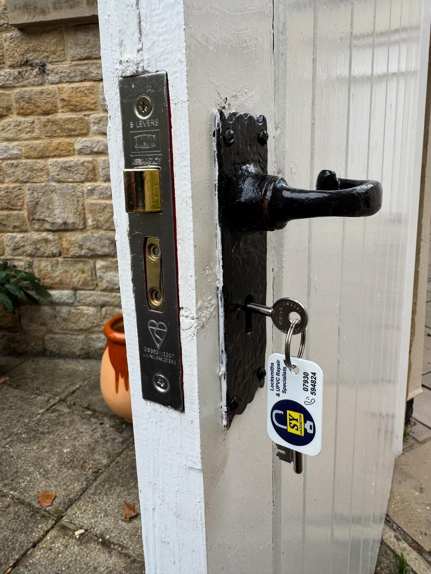 Close-up of a door handle and lock mechanism with a stone wall background