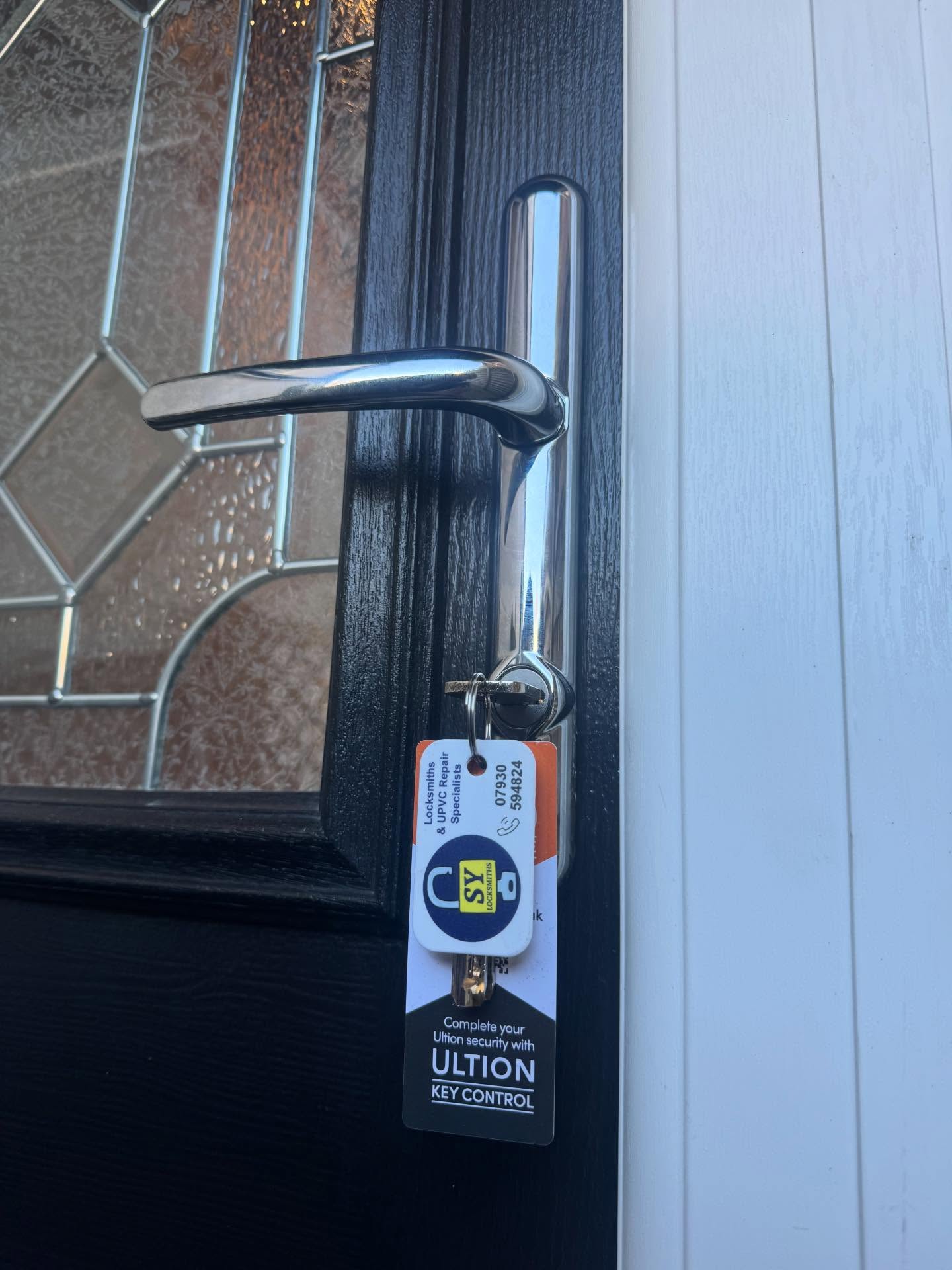 Door lock with a SY Locksmiths in Millhouses key tag attached fitted to a black door.