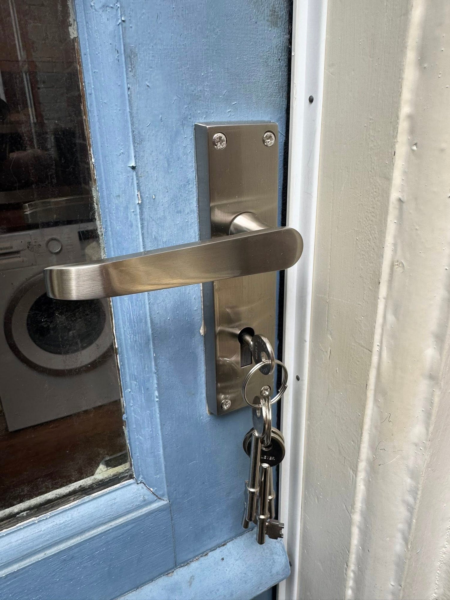 Close-up of a door handle with keys on a blue door after gaining entry to mortice lock