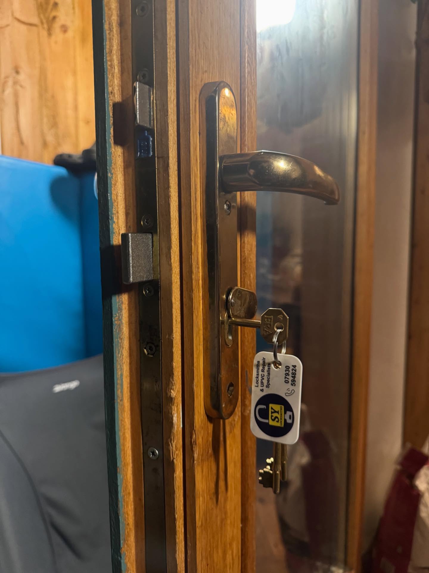 Wooden door with handle and lock mechanism, showing a key and key tag after lock opened.