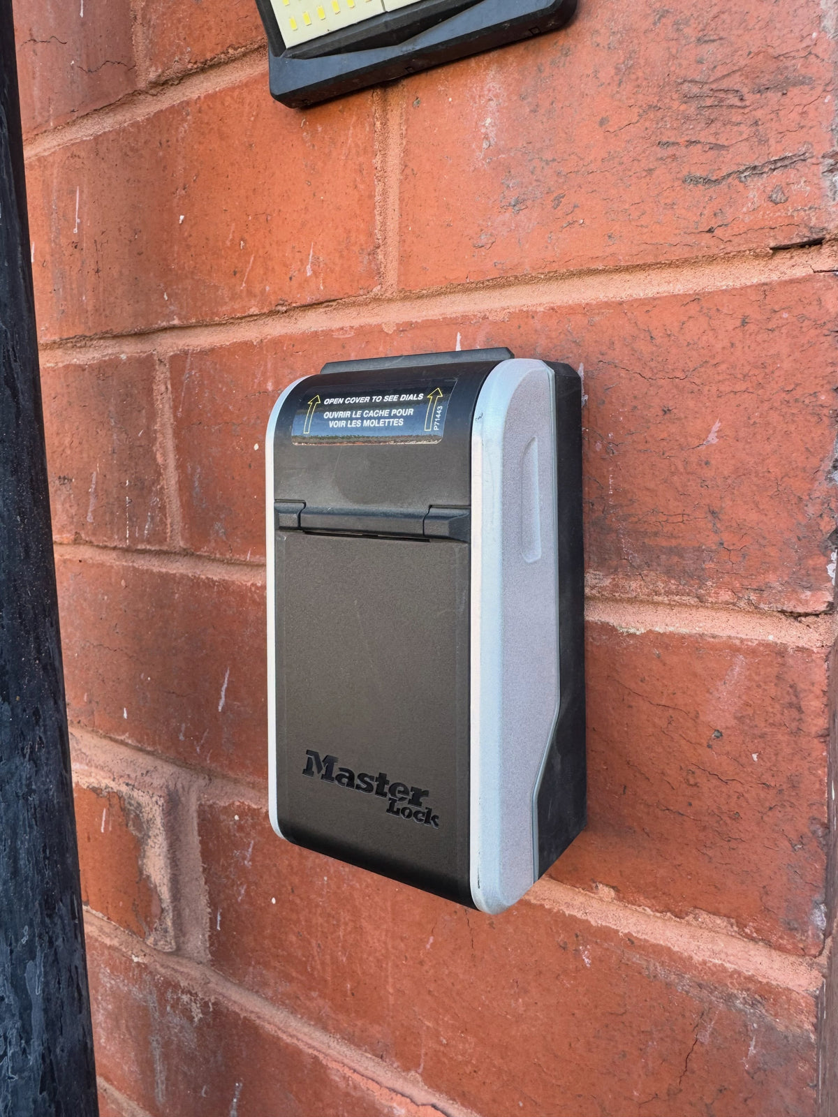 Master Lock keysafe in black fitted to red brick wall outside of property in Darnall