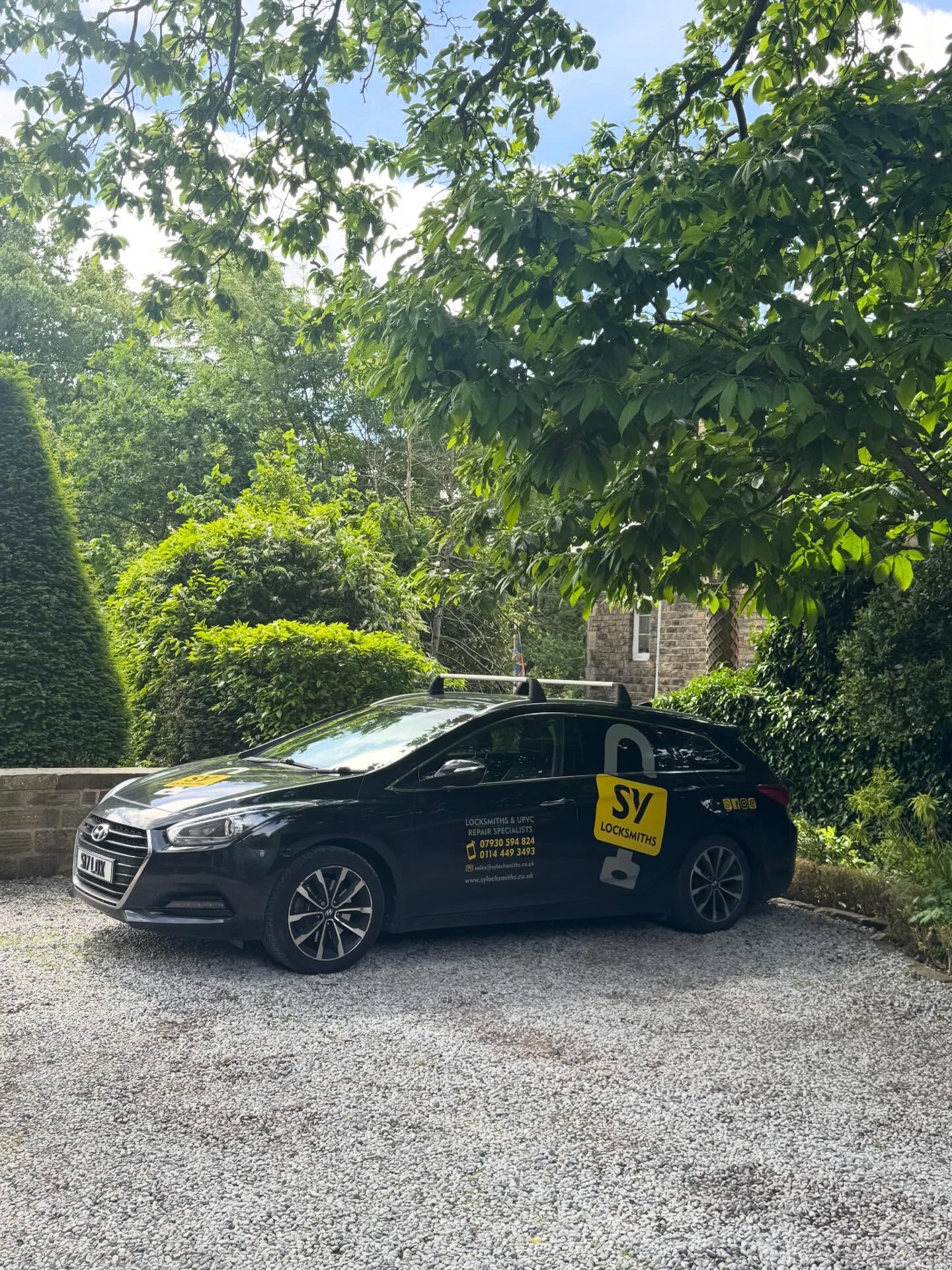 SY Locksmiths black car with yellow signage parked on a gravel driveway in Darnall surrounded by greenery