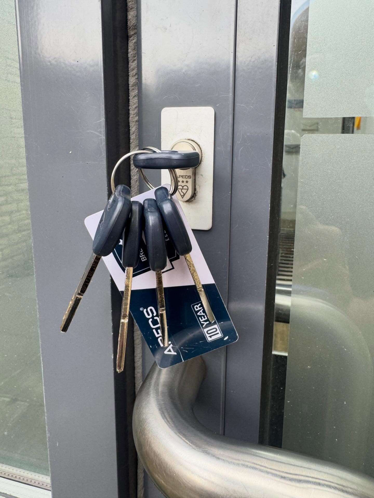 Apecs 3 star anti snap lock fitted to grey aluminium door showing 10 year guarantee card in white and blue   