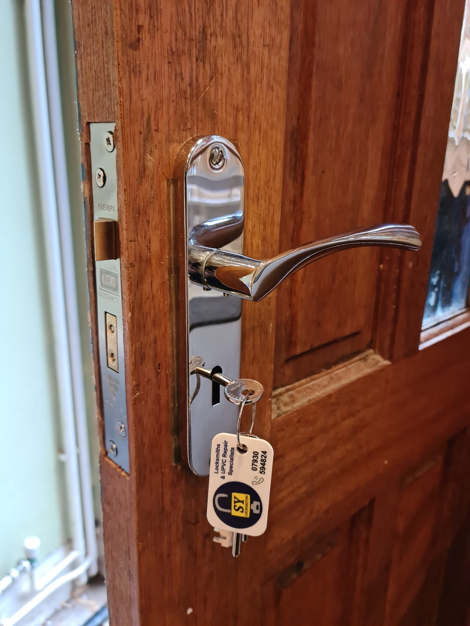 Close-up of a wooden door with a union 2134 BS3621 sash lock with a silver handle and key in a lock